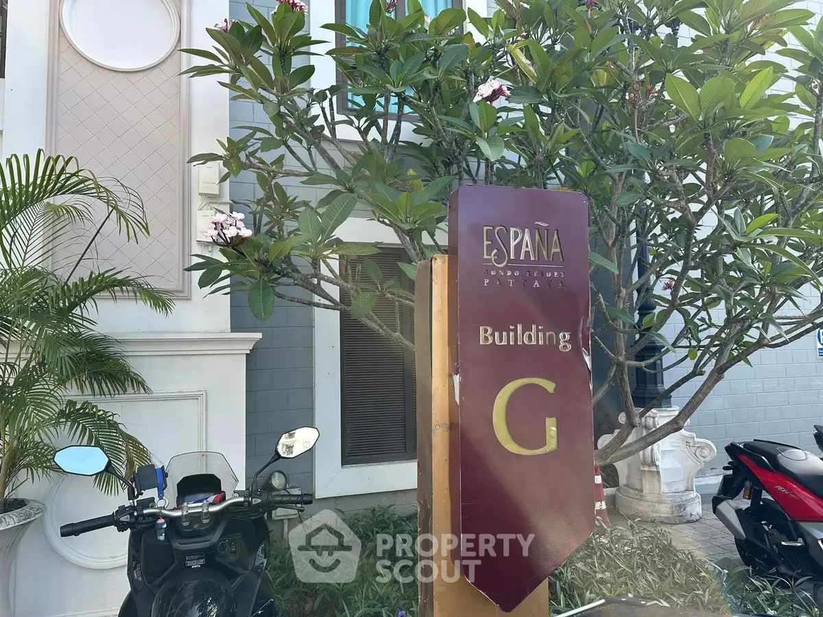 Elegant building entrance with lush greenery and modern signage at España complex.