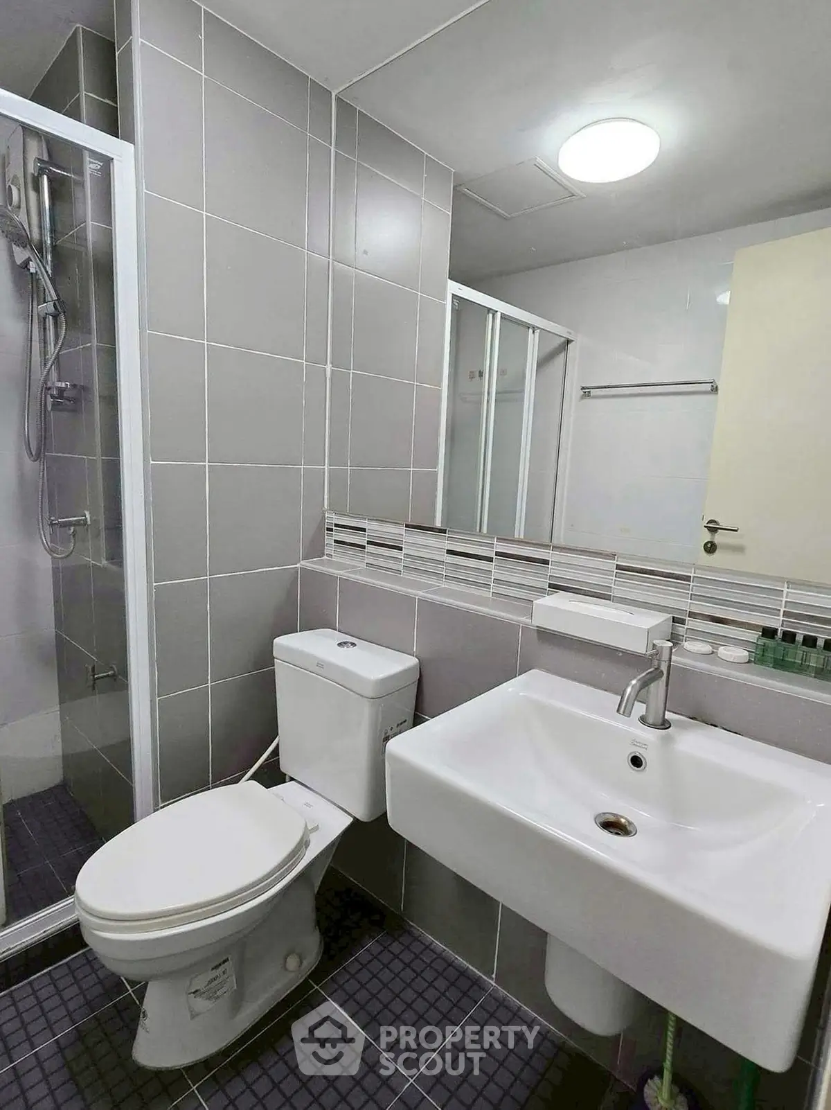 Modern bathroom with sleek fixtures and glass shower enclosure in contemporary apartment.
