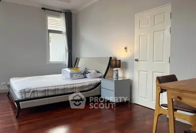 Spacious bedroom with elegant wooden flooring and modern furniture