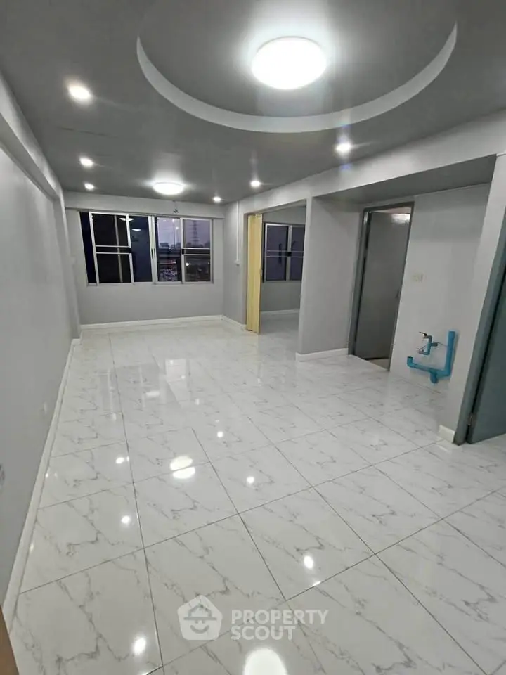 Spacious modern living room with elegant white marble flooring and recessed lighting.