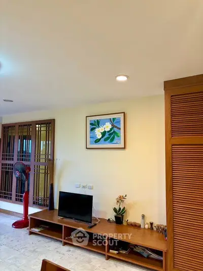 Charming living room with modern decor and wooden accents, featuring a cozy entertainment setup.