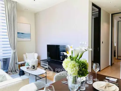 Modern living room with elegant decor and natural light, featuring a sleek TV setup and stylish dining area.