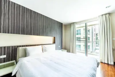 Modern bedroom with large window and stylish decor in a luxury apartment.