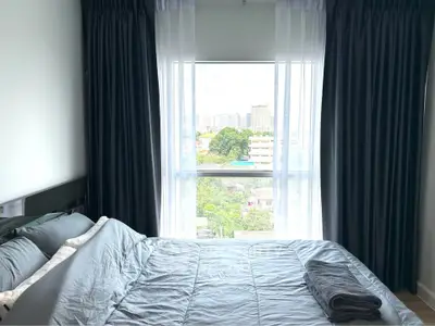 Cozy bedroom with large window offering a stunning city view, perfect for relaxation and comfort.