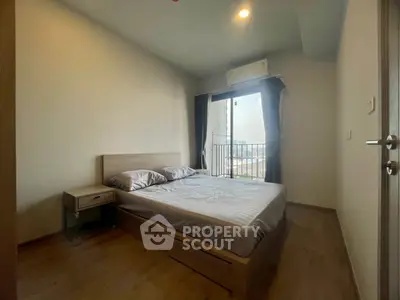 Cozy bedroom with modern furnishings and balcony view, perfect for urban living.