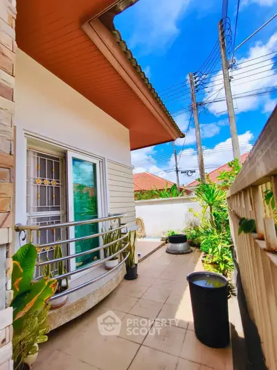 Charming outdoor balcony with lush greenery and bright blue sky, perfect for relaxation and enjoying nature.