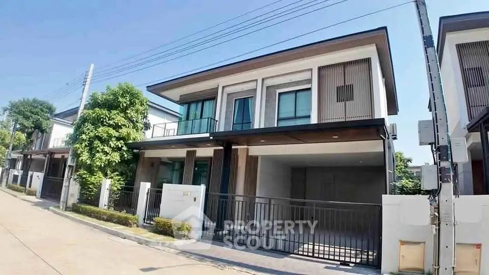 Modern two-story house with sleek design and spacious driveway in a suburban neighborhood.