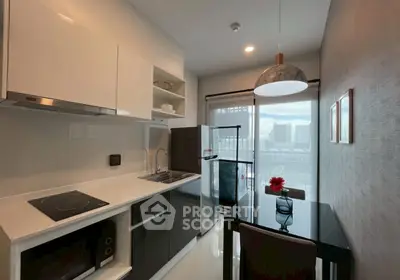 Modern kitchen with sleek appliances and dining area, featuring a stylish pendant light and scenic window view.