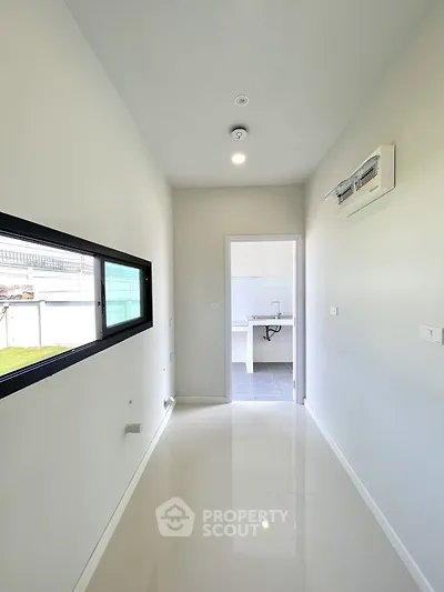 Bright hallway leading to a modern kitchen with sleek white finishes.