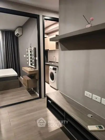 Modern apartment interior with bedroom and kitchen featuring washing machine and sleek design.