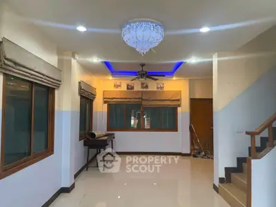 Spacious living room with modern chandelier and staircase, ideal for family gatherings.