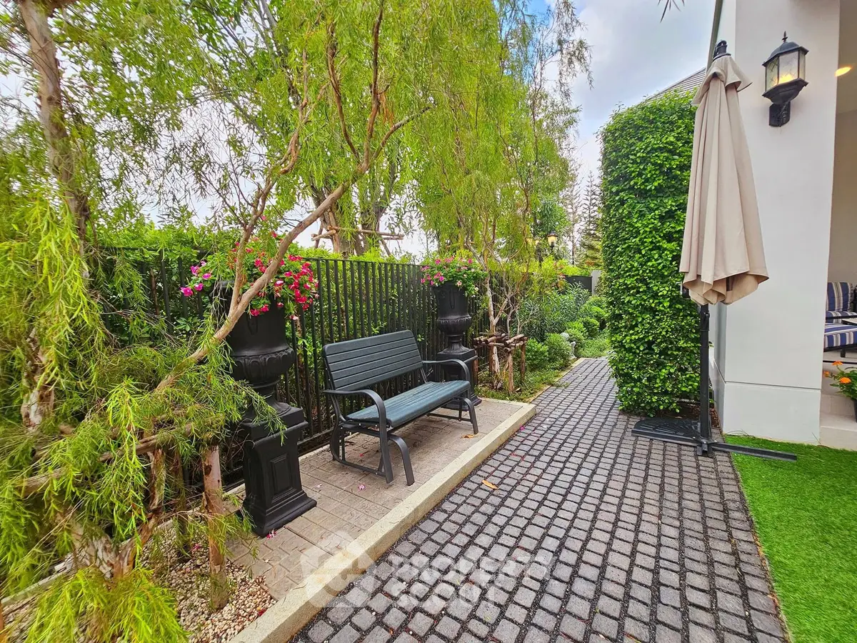 Charming garden patio with bench and lush greenery, perfect for relaxation.