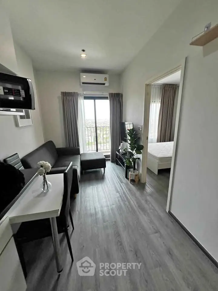 Modern living room with sleek furniture and large window offering natural light and scenic views.
