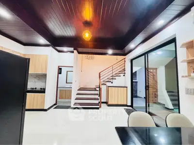 Modern open-plan living area with sleek kitchen and stylish staircase in contemporary home.