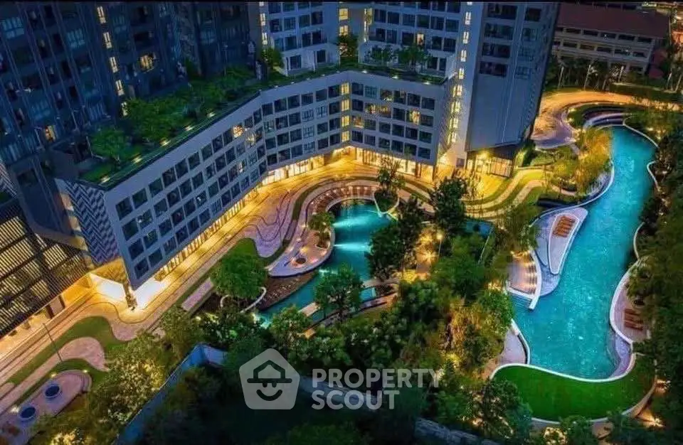 Luxurious apartment complex with stunning illuminated pool and lush gardens at night.