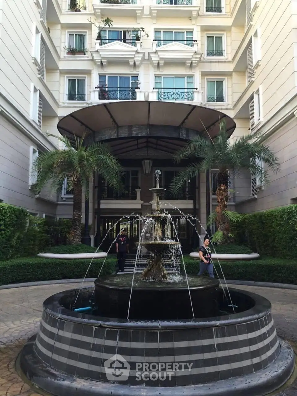 Elegant building entrance with a central fountain and lush greenery