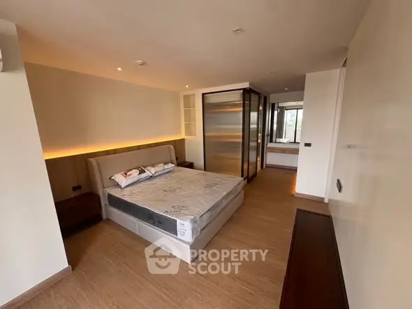 Spacious modern bedroom with elegant design and ample natural light, featuring a cozy bed and sleek wooden flooring.