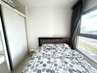Modern bedroom with large window and geometric bedding in a high-rise apartment.