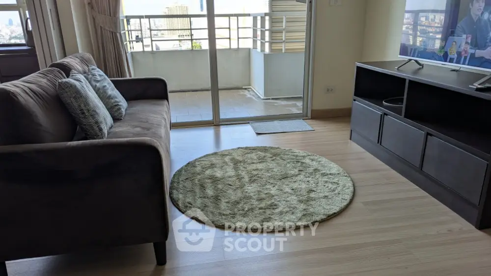 Modern living room with balcony view, featuring cozy sofa and entertainment unit.