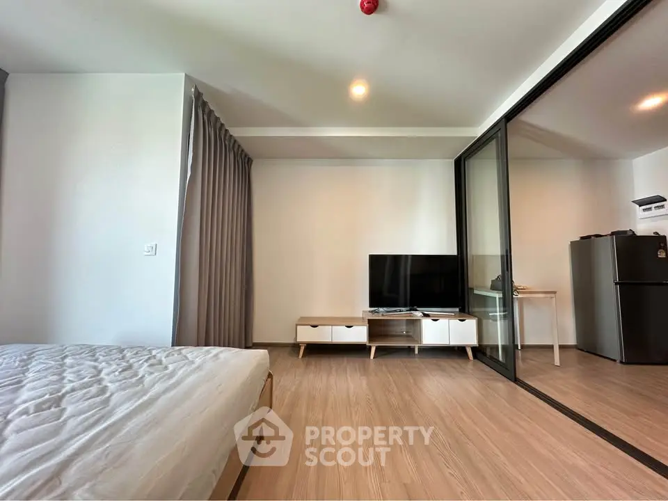 Modern studio apartment with sleek design and glass partition, featuring a cozy living area and stylish furnishings.