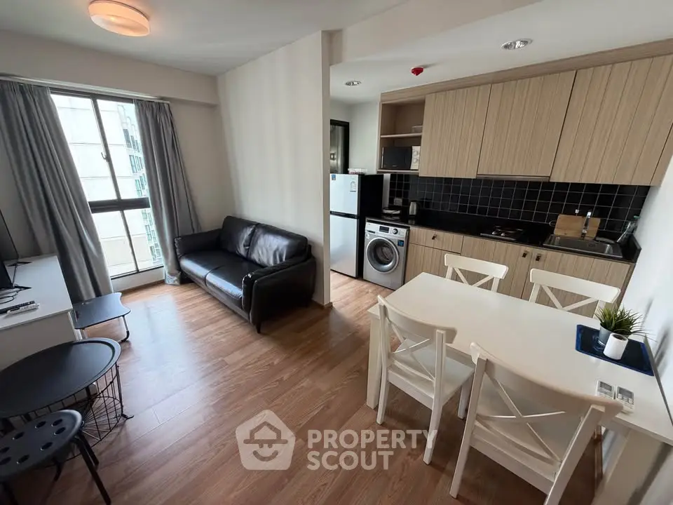 Modern open-layout living room with kitchen, featuring wooden floors and stylish furniture.