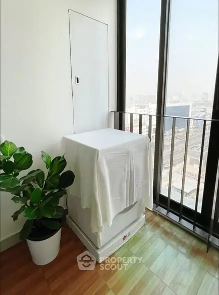 Bright balcony with city view and potted plant, perfect for relaxation.