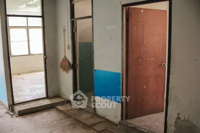 Unfinished interior space with open doors and broom, potential for renovation.