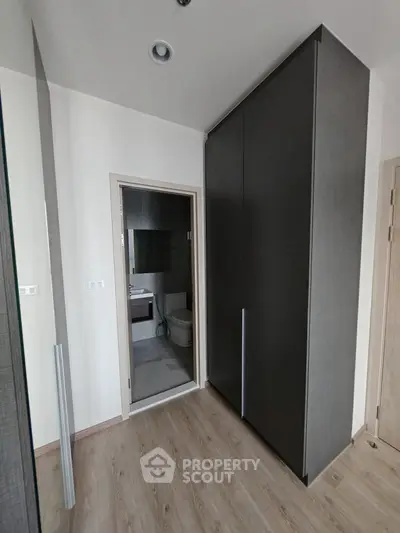 Modern bathroom entrance with sleek storage cabinets and wooden flooring