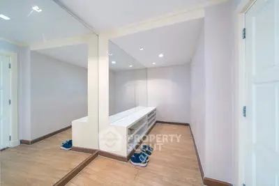 Spacious walk-in closet with mirrored walls and wooden flooring