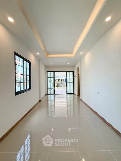 Spacious modern living room with sleek tile flooring and large windows for natural light.