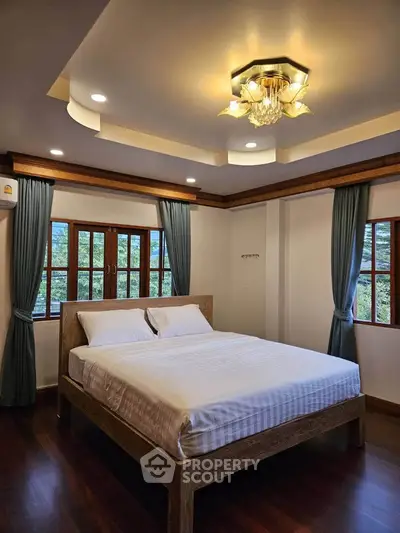 Spacious bedroom with elegant lighting and large windows offering scenic views.