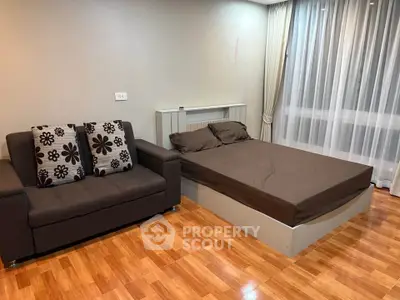 Modern bedroom with wooden flooring, cozy sofa, and large window with sheer curtains.