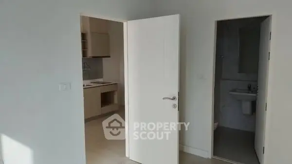 Bright minimalistic interior with open door leading to kitchen and bathroom