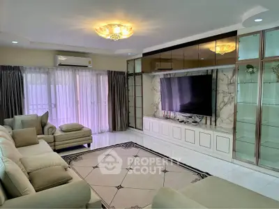 Luxurious living room with elegant decor, large TV, and plush seating in a modern home.