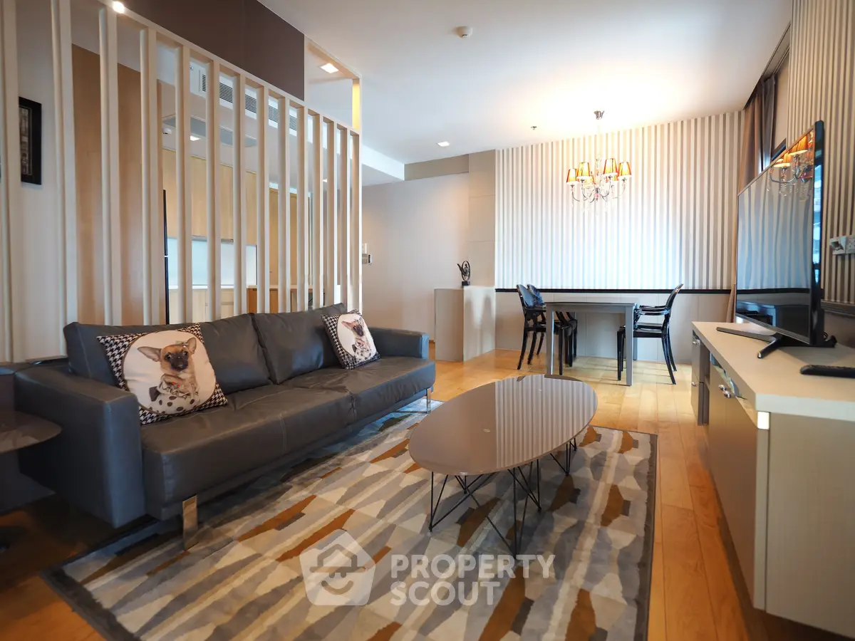 Modern living room with stylish decor and open dining area, featuring a sleek sofa and contemporary lighting.