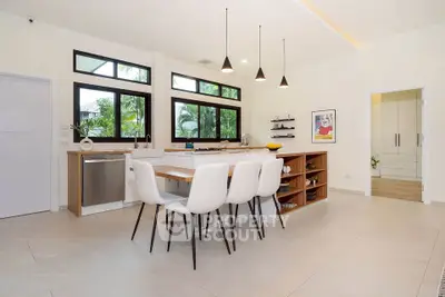 Modern kitchen with open layout, sleek design, and natural light, featuring a dining area and stylish pendant lights.