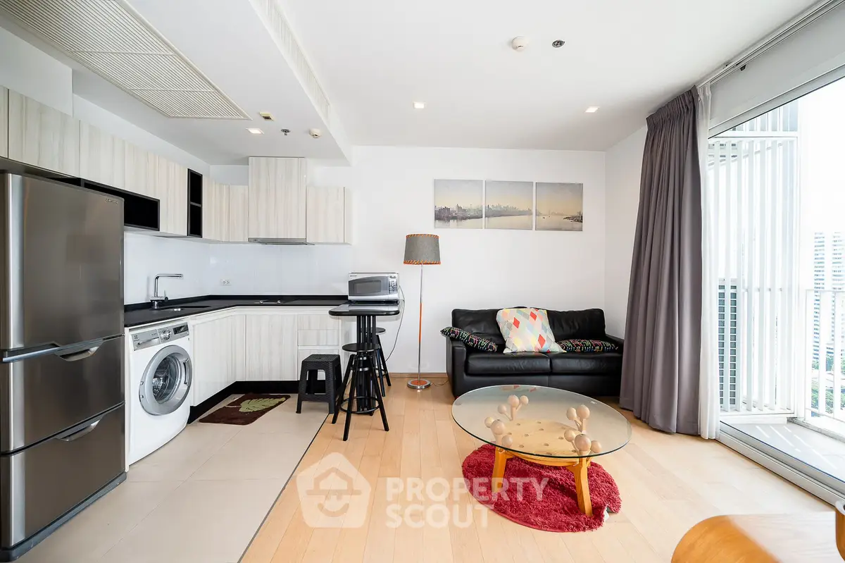 Modern open-plan living room with kitchen, featuring sleek appliances and city view balcony.