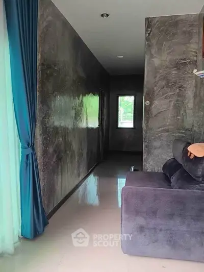Modern hallway with polished floors and elegant blue curtains, leading to a cozy living area.