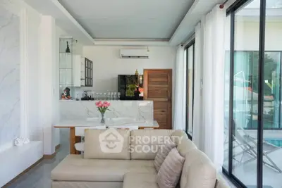 Luxurious living room with modern open kitchen and poolside view, featuring elegant decor and ample natural light.