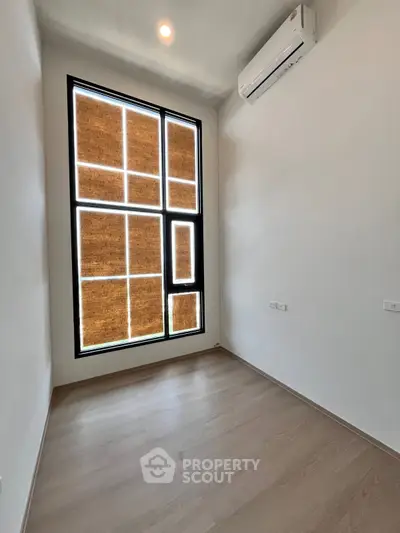 Spacious empty room with large windows and modern air conditioning unit, perfect for customization.