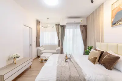 Luxurious bedroom with elegant decor and natural light, featuring a cozy seating area and modern furnishings.