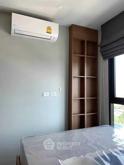 Modern bedroom with air conditioning and built-in shelving, offering comfort and functionality.
