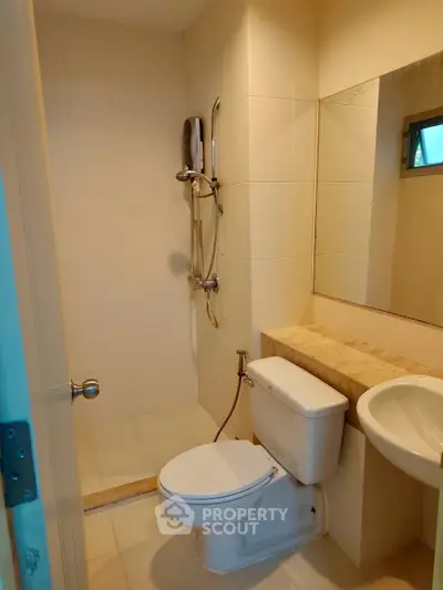 Modern bathroom with sleek fixtures and neutral tiles, featuring a shower and toilet.
