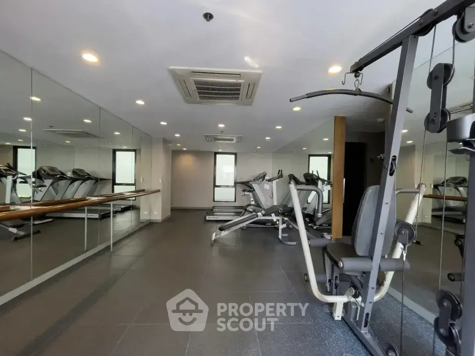 Modern gym with fitness equipment and mirrored walls in a residential building.