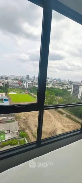 Stunning cityscape view from high-rise apartment window, showcasing urban skyline and greenery.