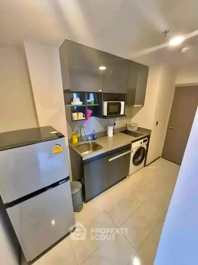 Modern compact kitchen with sleek cabinetry and integrated appliances in urban apartment.
