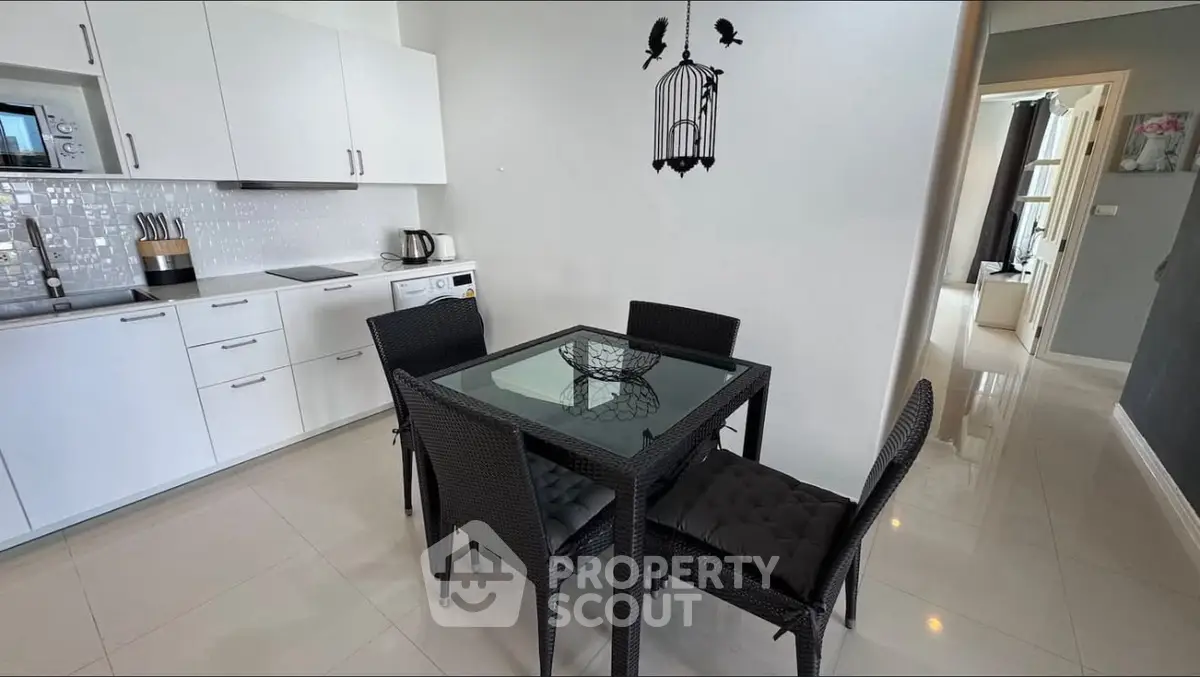 Modern kitchen with sleek white cabinets and cozy dining area, perfect for urban living.