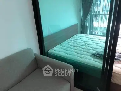 Modern bedroom with glass partition and cozy sofa, featuring a balcony view.