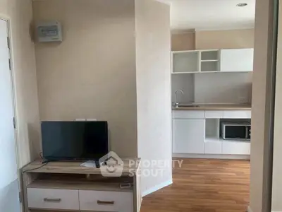 Modern apartment interior with compact kitchen and cozy living area featuring wooden flooring.