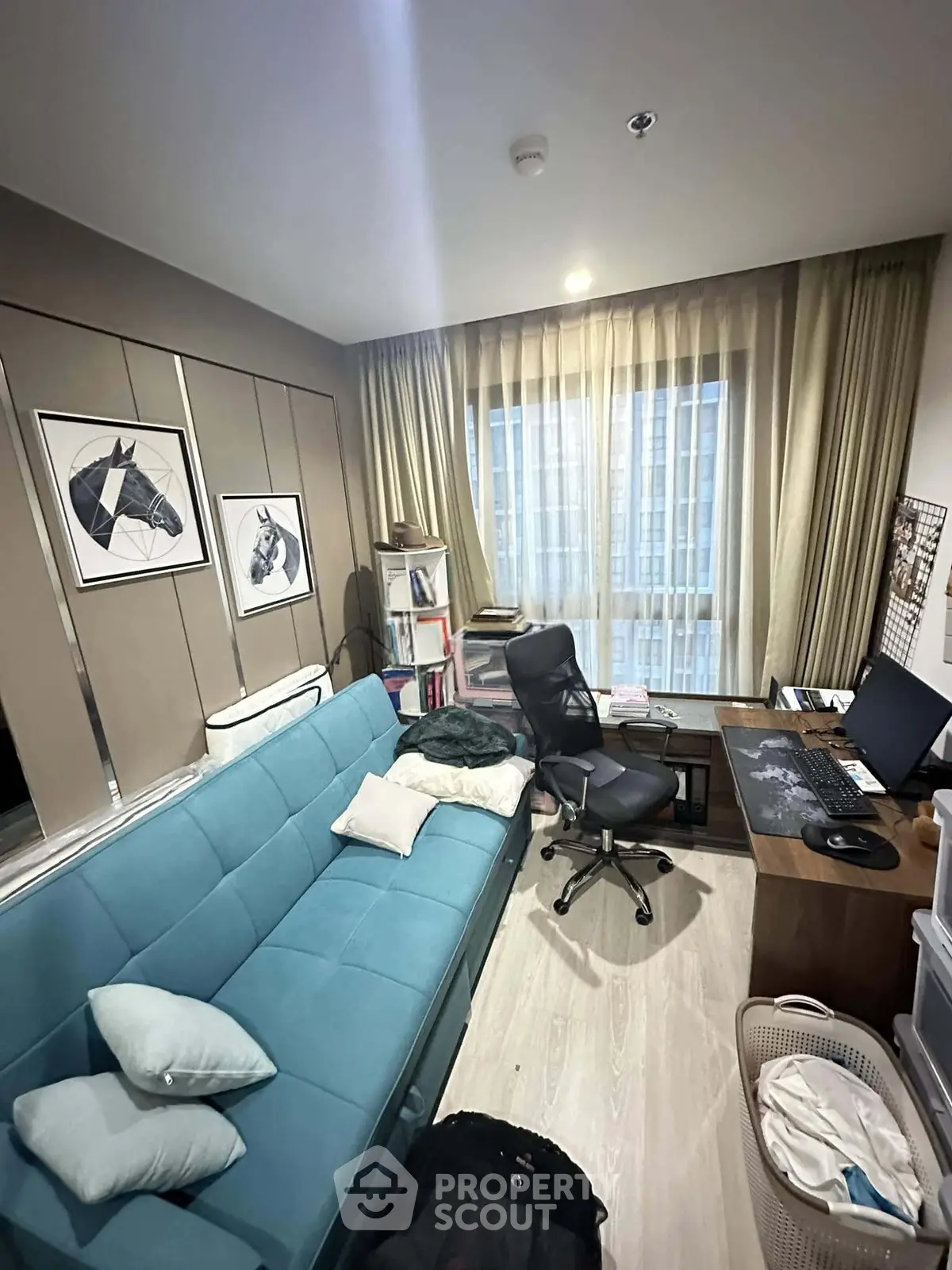 Cozy study room with modern decor and natural light, featuring a blue sofa and work desk.